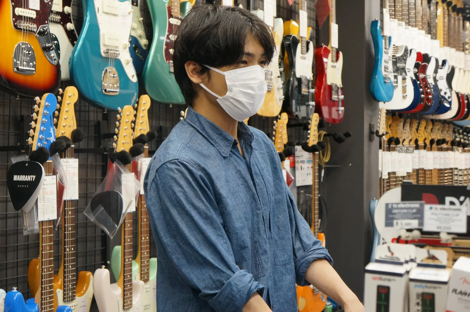Staff at Gakkiya BOW, in front of a wall of guitars